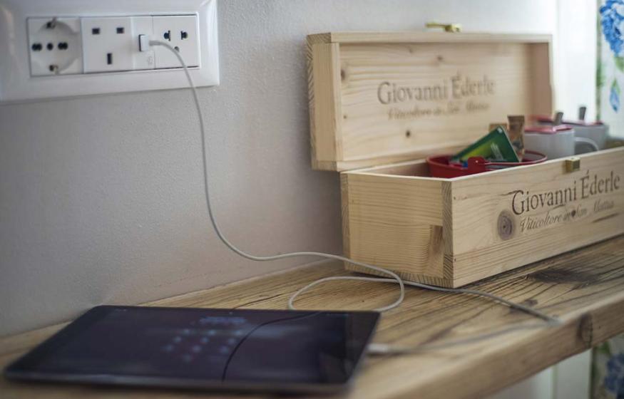 Tablet in carica accanto a una scatola di legno su uno scaffale.