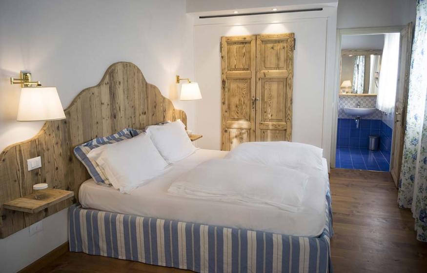 Camera accogliente con letto matrimoniale, legno rustico e bagno privato.